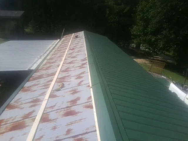 Old rusted panels beside newly installed green metal roofing — Wind Damage Roof Repair by Roofing Brothers in Winsted