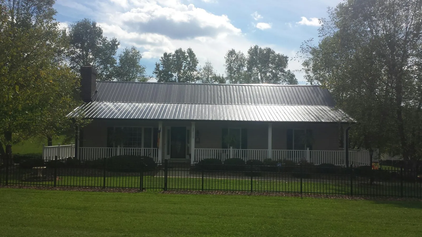 Gray metal roof on a brick ranch with a full width front porch — Gutter Guard Installation work by our crew in Winsted